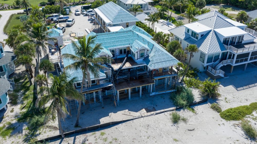 Aerial view of a beachfront home under construction with new roof underlayment and scaffolding