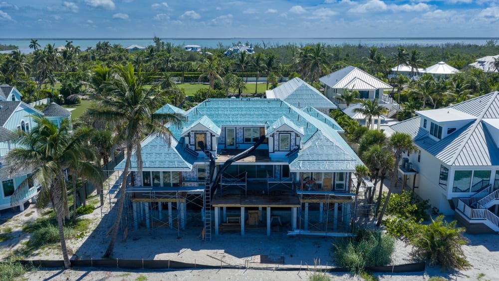 Aerial view of an elevated beachfront home under construction with the Gulf of Mexico behind it