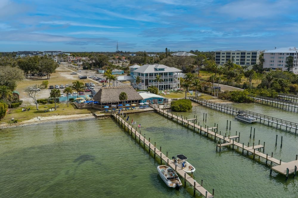 Aerial view of a marina restaurant, wooden boat docks and clear green Gulf water