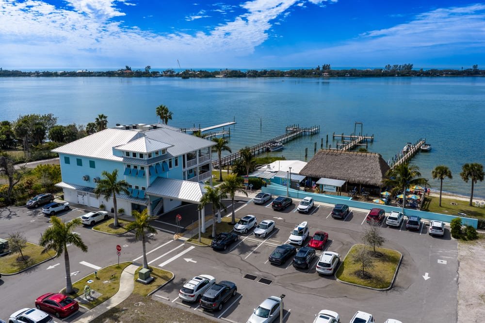 Aerial view of a waterfront restaurant with tiki hut, boat docks and a full parking lot on the Intracoastal