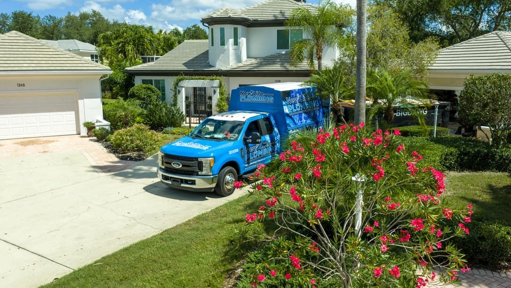 A branded home-service company truck at a luxury Florida home with tropical landscaping