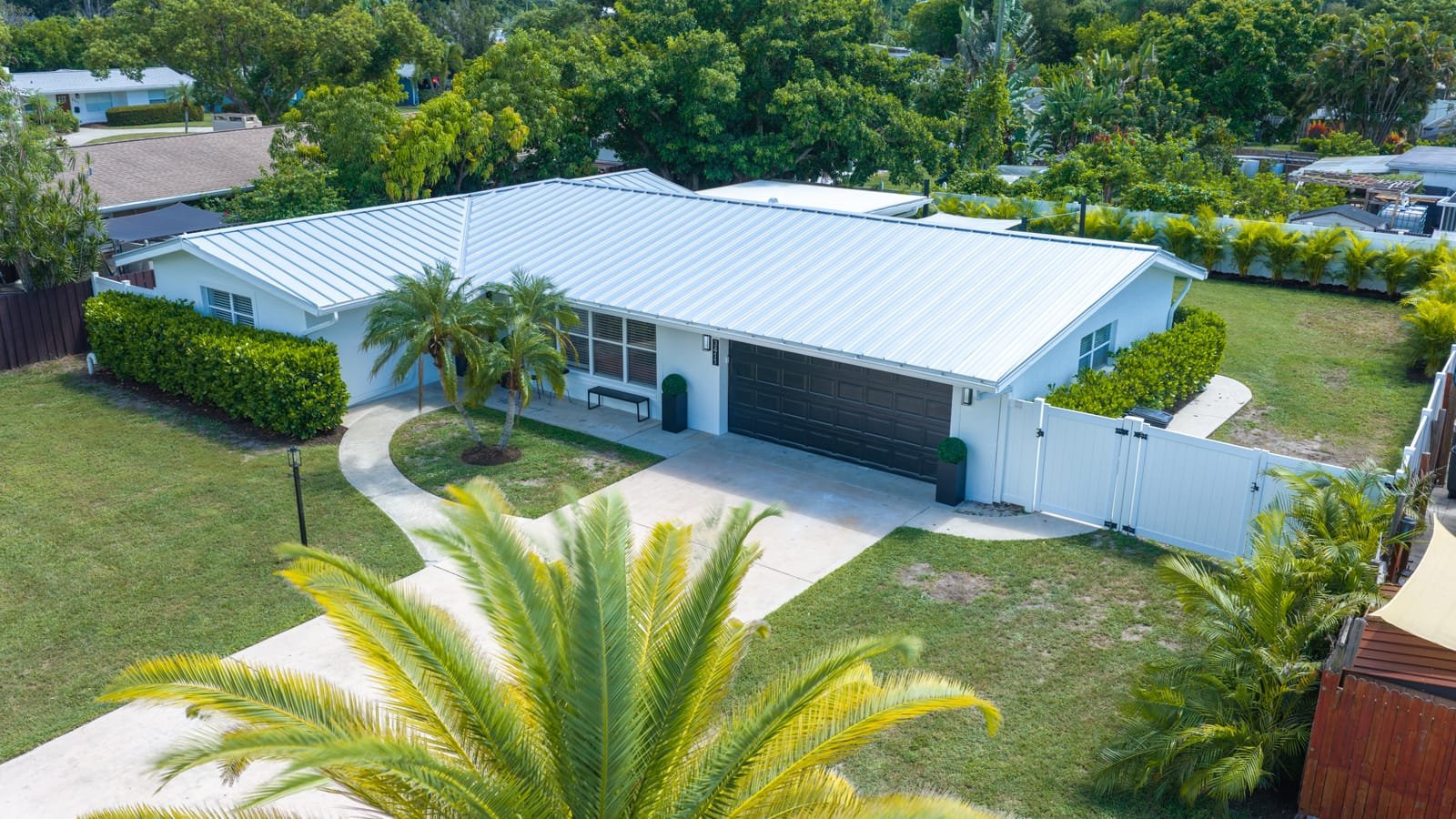 Aerial view of a single-storey Sarasota home with a metal roof, palm-planted front yard and driveway